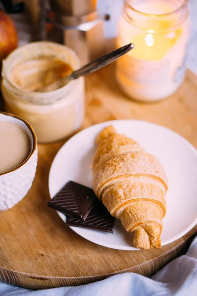 Cozy winter weekend breakfast, coffee and croissant on wooden tray — Stock Photo, Image