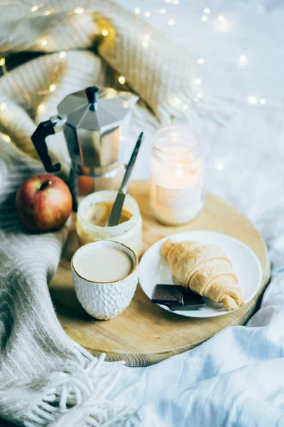 Útulná zimní víkendová snídaně, káva a croissant na dřevěném podnosu — Stock fotografie