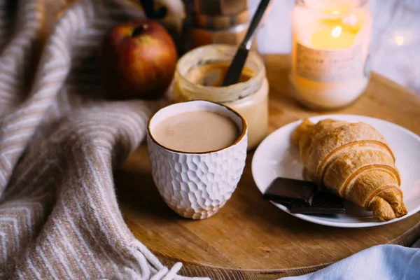 Cozy winter weekend breakfast, coffee and croissant on wooden tray — Stock Photo, Image