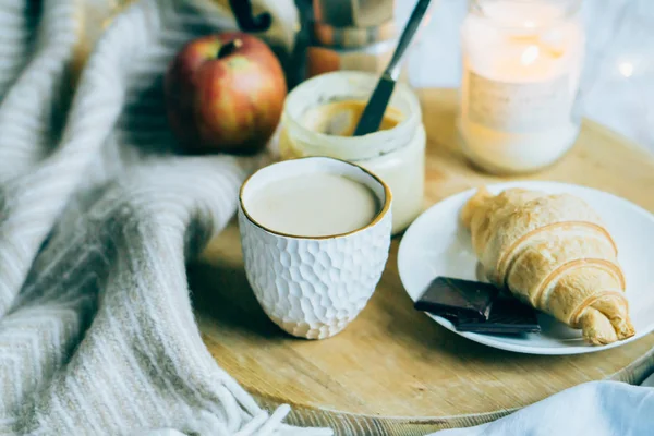 Cozy winter weekend breakfast, coffee and croissant on wooden tray — Stock Photo, Image