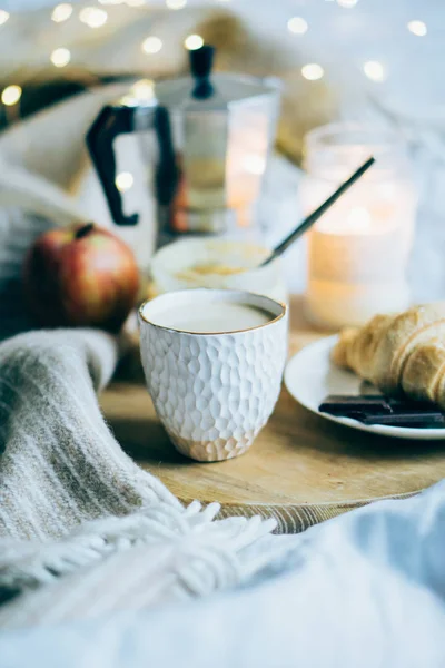 Útulná zimní víkendová snídaně, káva a croissant na dřevěném podnosu — Stock fotografie