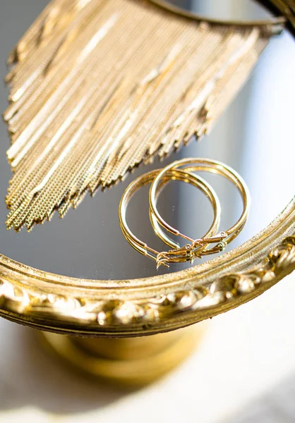 Brincos dourados e colar na bandeja de espelho — Fotografia de Stock