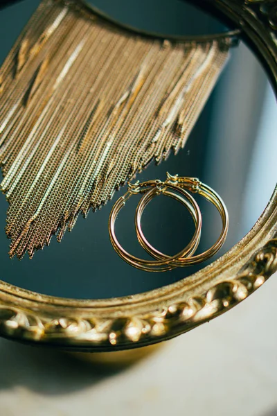 Boucles d'oreilles et collier dorés sur plateau miroir — Photo