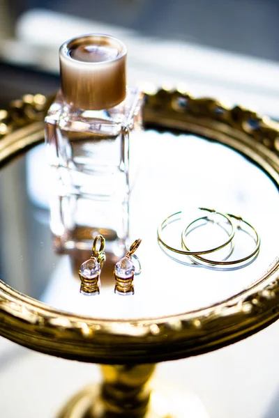 Golden earrings with gemstones and perfume on mirror tray — Stock Photo, Image