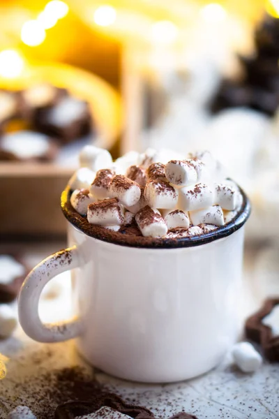 Comforting Christmas food, mug of hot cocoa with marshmallow and cookies with cozy lights