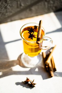 Hot winter drink with cinnamon and lemon on bright sunny day