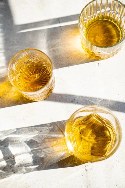 Ουίσκι σε ποτήρια στο τραπέζι σε έντονο ηλιακό φως, κίτρινο ποτό — Φωτογραφία Αρχείου