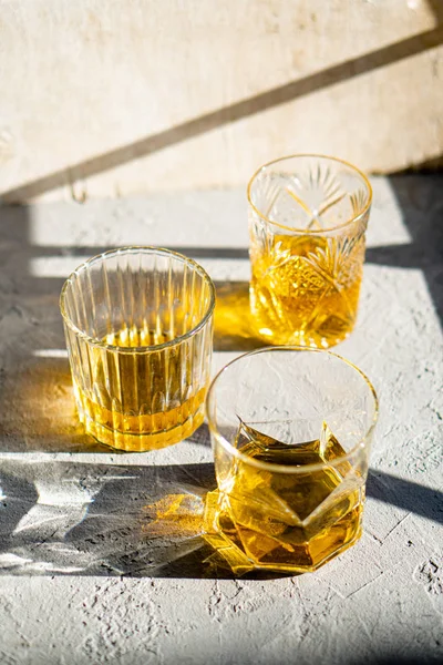 明るい太陽の下でテーブルの上のガラスの上のウイスキー、黄色のドリンク — ストック写真