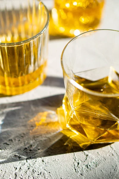 Whisky in Gläsern auf dem Tisch im hellen Sonnenlicht, gelbes Getränk — Stockfoto