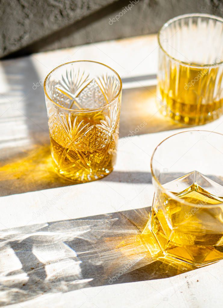 Whiskey in glasses on table in bright sunlight, yellow drink
