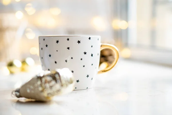 Acogedora decoración de vacaciones de invierno, luces de Navidad y taza de café con detalles de decoración, hogar real — Foto de Stock