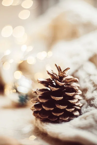 Cono de pino pintado de oro en manta de punto sobre fondo de decoración navideña —  Fotos de Stock