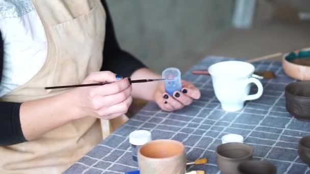 Kobiet ręka malowanie biały ceramiczny kubek, garncarze studio warsztatowe — Wideo stockowe