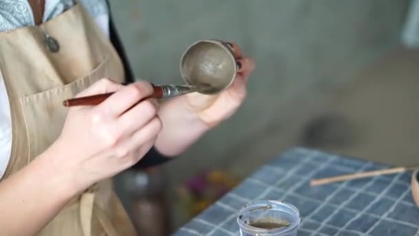 Womans hand painting brown clay cup, potters workshop studio — Stock Video