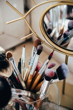 Sanatçının stüdyosunda ayna yansımalı birçok farklı makyaj fırçası var.