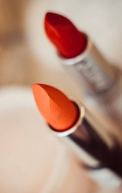 Orange and red lipsticks close-up, real make-up tools macro