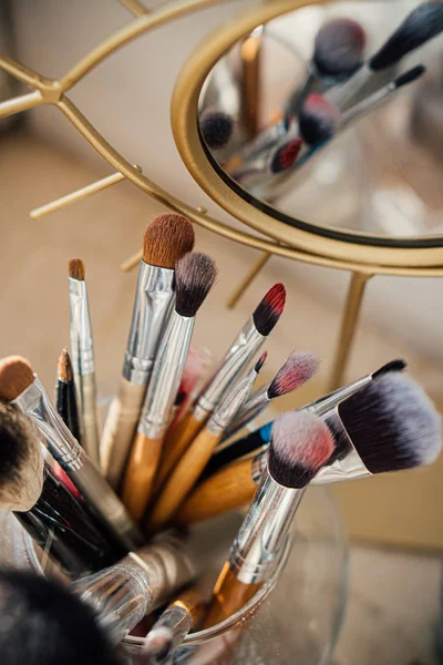 Molti pennelli per trucco diversi in studio di artisti con riflesso a specchio — Foto Stock