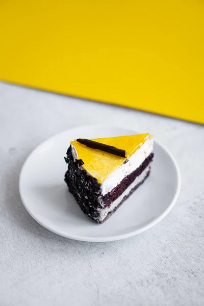 Slice of chocolate cake with yellow jelly top on white table — Stock Photo, Image
