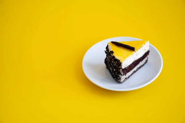 Sneetje chocoladetaart met sinaasappelgelei op platte gele achtergrond — Stockfoto