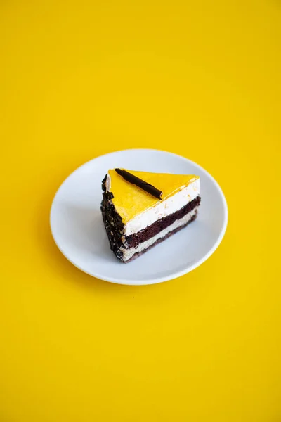 Φέτα κέικ σοκολάτας με μαρμελάδα πορτοκάλι κορυφή σε επίπεδο κίτρινο φόντο — Φωτογραφία Αρχείου