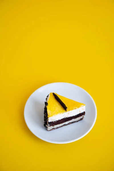Φέτα κέικ σοκολάτας με μαρμελάδα πορτοκάλι κορυφή σε επίπεδο κίτρινο φόντο — Φωτογραφία Αρχείου