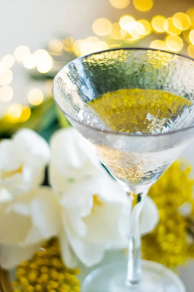 Boeket witte tulpen en mimosa bloemen op spiegelblad met glas drank — Stockfoto