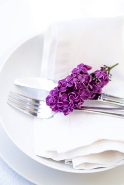 Beyaz keten peçetenin üzerinde leylak dalı olan bahar masası