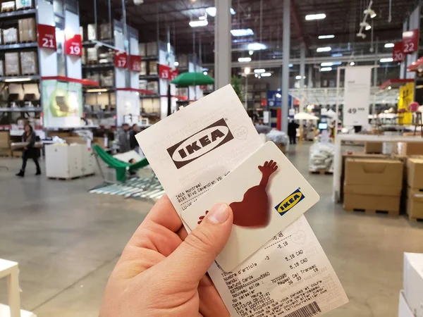 Rafların üzerinde hediye kartıyla IKEA makbuzu tutan bir el. — Stok fotoğraf