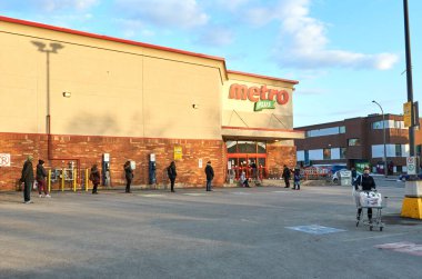 Montreal, Kanada - 24 Mart 2020: İnsanlar yiyecek dükkanına girmek için sosyal mesafelerini koruyorlar. Metro, Quebec ve Ontario eyaletlerinde faaliyet gösteren Kanadalı bir gıda perakendecisi..
