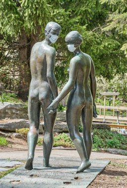 Laval, Kanada - 17 Mayıs 2020: Centre de la Nature Laval 'da koruyucu maskeli bir kadın ve erkeğin heykeli. Koronavirüs durumu nedeniyle pek çok heykelin farkında olmak için maske takılır.