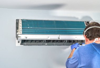 Montreal, Kanada - 24 Mayıs 2020: Mavi eldivenli ve maskeli teknisyen klimayı söküp temizlemeye hazırlıyor. Klimaların temizlenmesi içeride küflenmesini önler.