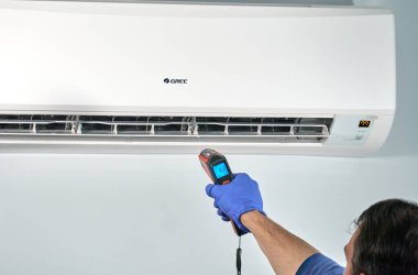 Gree klimasının içindeki kızılötesi termometreyle teknisyen kontrol ısısı.