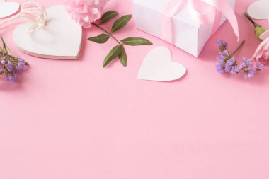Hediye, ahşap beyaz kalp ve pembe arka planda çiçekler.