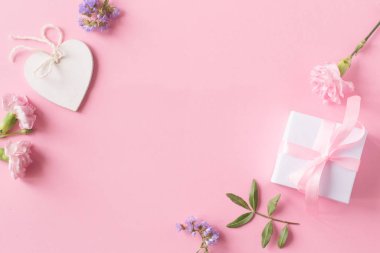 Hediye, ahşap beyaz kalp ve pembe arka planda çiçekler.