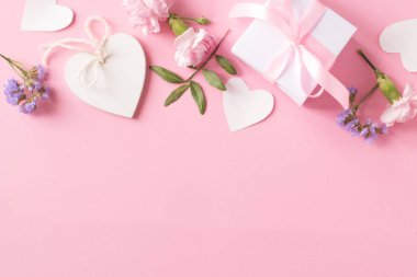 Hediye, ahşap beyaz kalp ve pembe arka planda çiçekler.