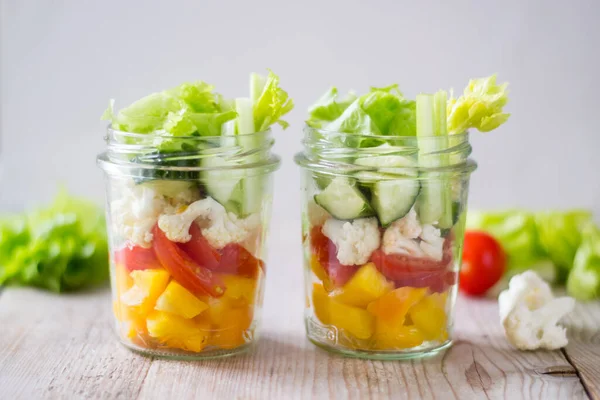 Healthy salad jar with celery, cherry tomatoes, cucumber, yellow pepper. Raw vegetarian meal for diet, detox, clean eating. Homemade concept.