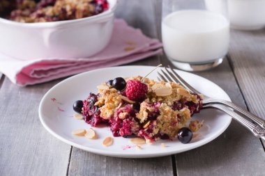 Gri ahşap zemin üzerinde beyaz tabakta böğürtlen parçacıkları.