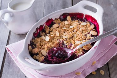 Böğürtlen, gri ahşap arka planda beyaz fırın kabında parçalanır..