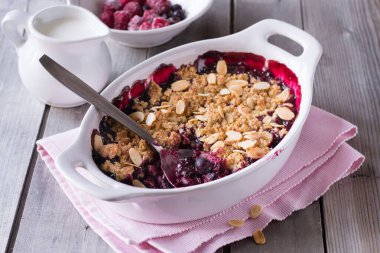 Böğürtlen, gri ahşap arka planda beyaz fırın kabında parçalanır..
