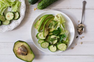 Sağlıklı sebze salatası taze salatalık, avokado, marul ve susam tohumu, kabak ve ayçiçeği tabakta. Diyet menüsü. Üst görünüm.