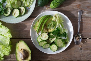 Sağlıklı sebze salatası taze salatalık, avokado, marul ve susam tohumu, kabak ve ayçiçeği tabakta. Diyet menüsü. Üst görünüm.