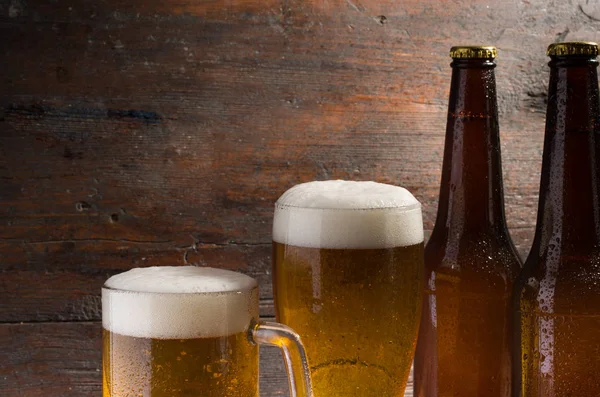 Butelki i kieliszki z piwem na stół z drewna — Zdjęcie stockowe