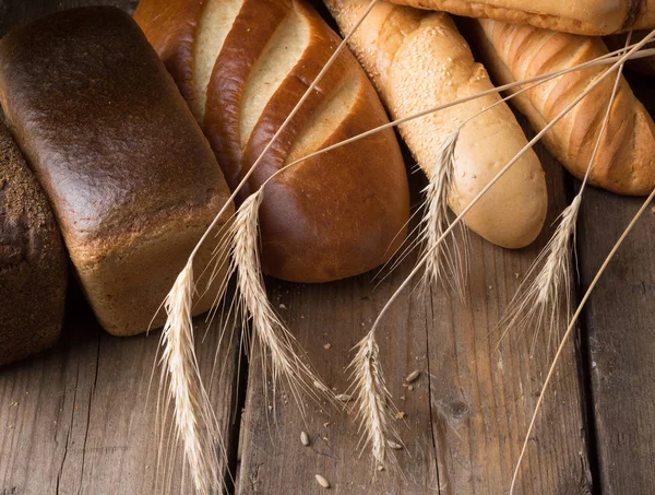 Różnych rodzajów chleba na drewnianym stołem — Zdjęcie stockowe