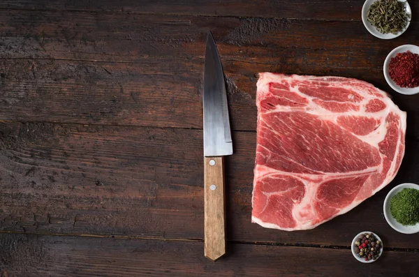 Carne de cerdo y cuchillo sobre tabla de madera . — Foto de Stock