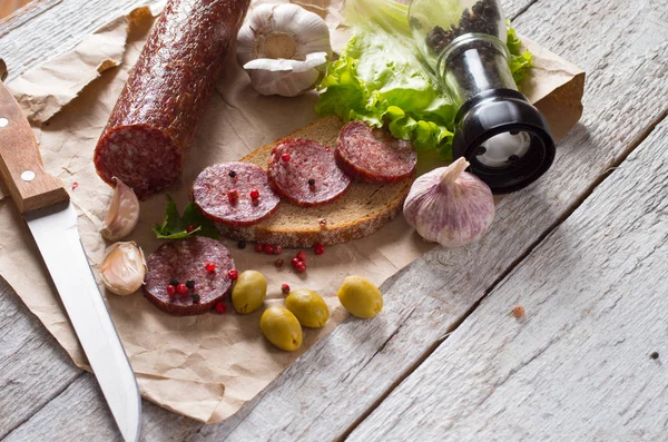 Salami et pain sur une planche de bois — Photo