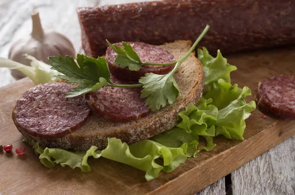 Salami en brood op een houten plank — Stockfoto