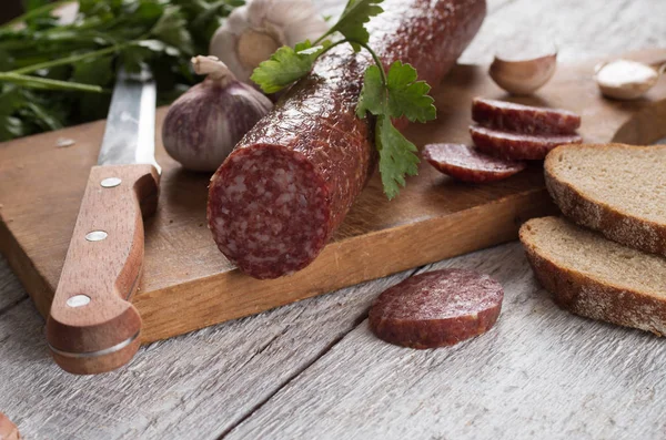 Salami et pain sur une planche de bois — Photo