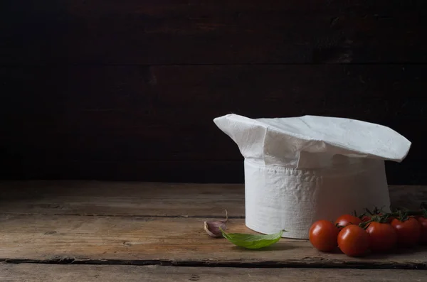 Sombrero de chef sobre una vieja mesa de madera . — Foto de Stock