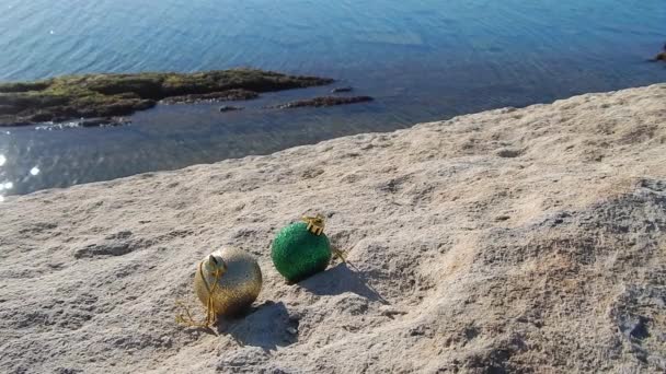 Πράσινο Και Χρυσό Παιχνίδι Χριστουγεννιάτικο Δέντρο Μια Βραχώδη Παραλία — Αρχείο Βίντεο