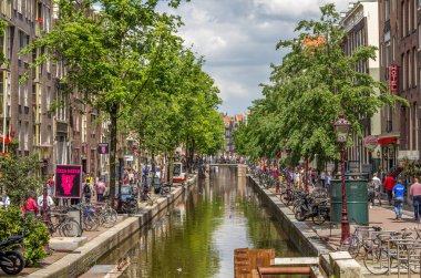 Amsterdam, Hollanda - 31 Mayıs 2014: Amsterdam 'da bir kanalda yürüyen turistler. Amsterdam Hollanda 'nın başkentidir ve kanallar ve limanlar şehir yüzeyinin dörtte birini doldurur..